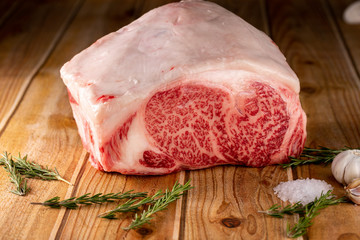 Kemikli A5 Wagyu ribeye bloğu, biberiye ve kaya tuzu ile ahşap üzerinde